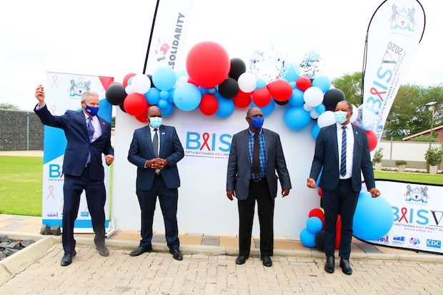Four people pose for photos in front of BAIS branded materials.