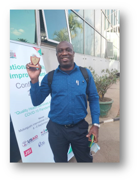 Adebayo Adedayo holding the QI conference award