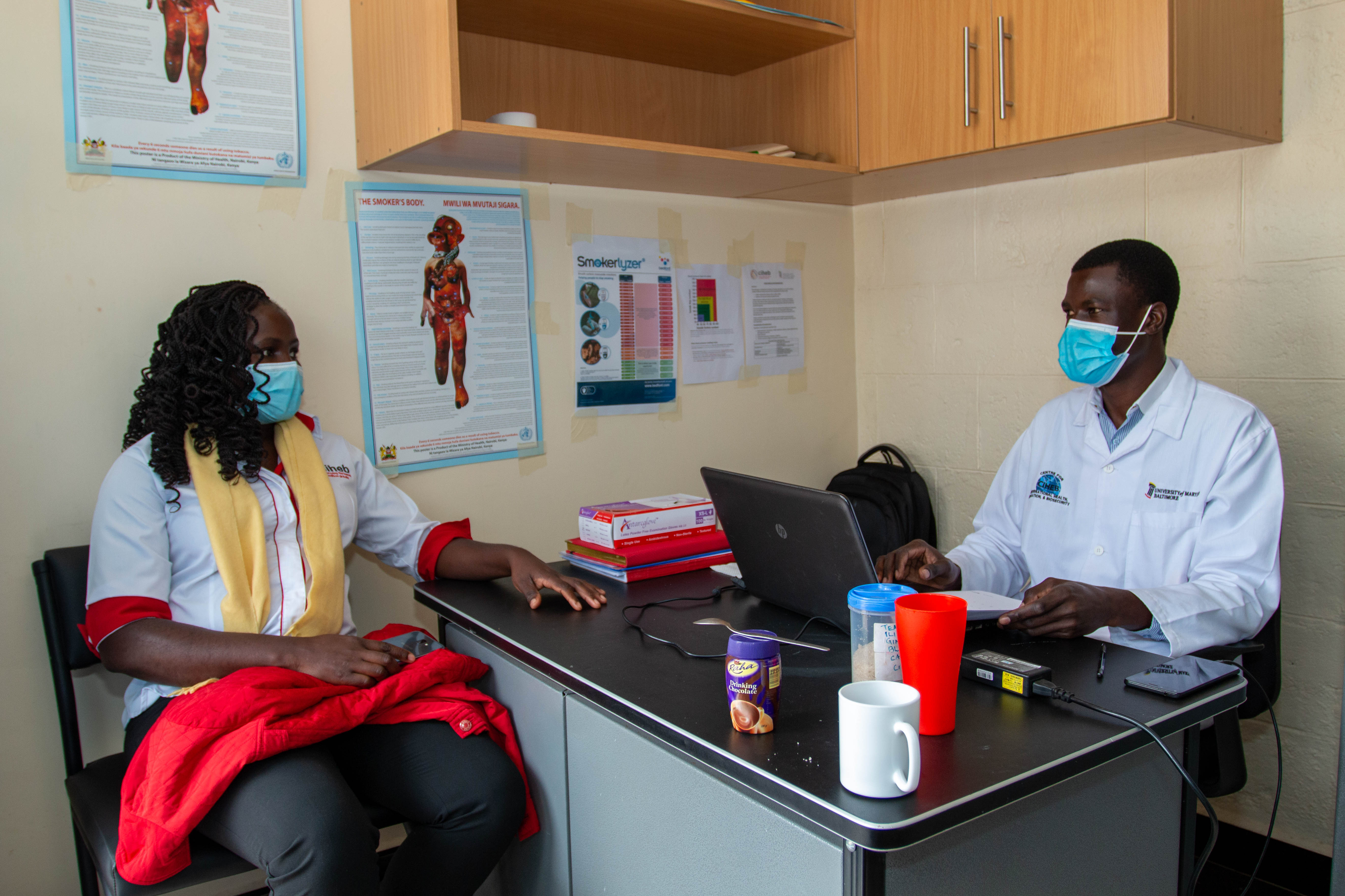 Patience Odour, study coordinator, talks with Patrick Odek, research assistant for the smoking cessation study.