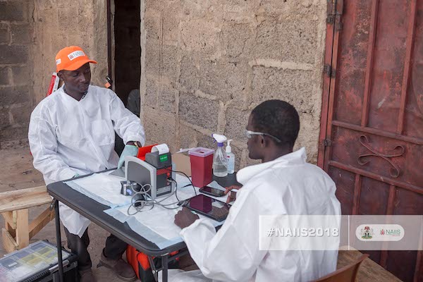 Two men wearing white gowns sit at a table across from each other.