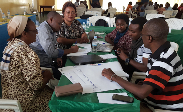 A group of people meeting and working around a table.