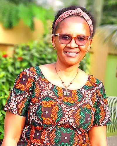 A woman wears a headband and a multi-colored blouse.