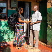 A woman and man talk outside his home.