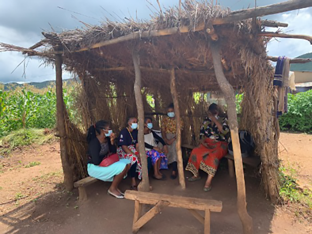 Five people sit in a shaded safe space location.